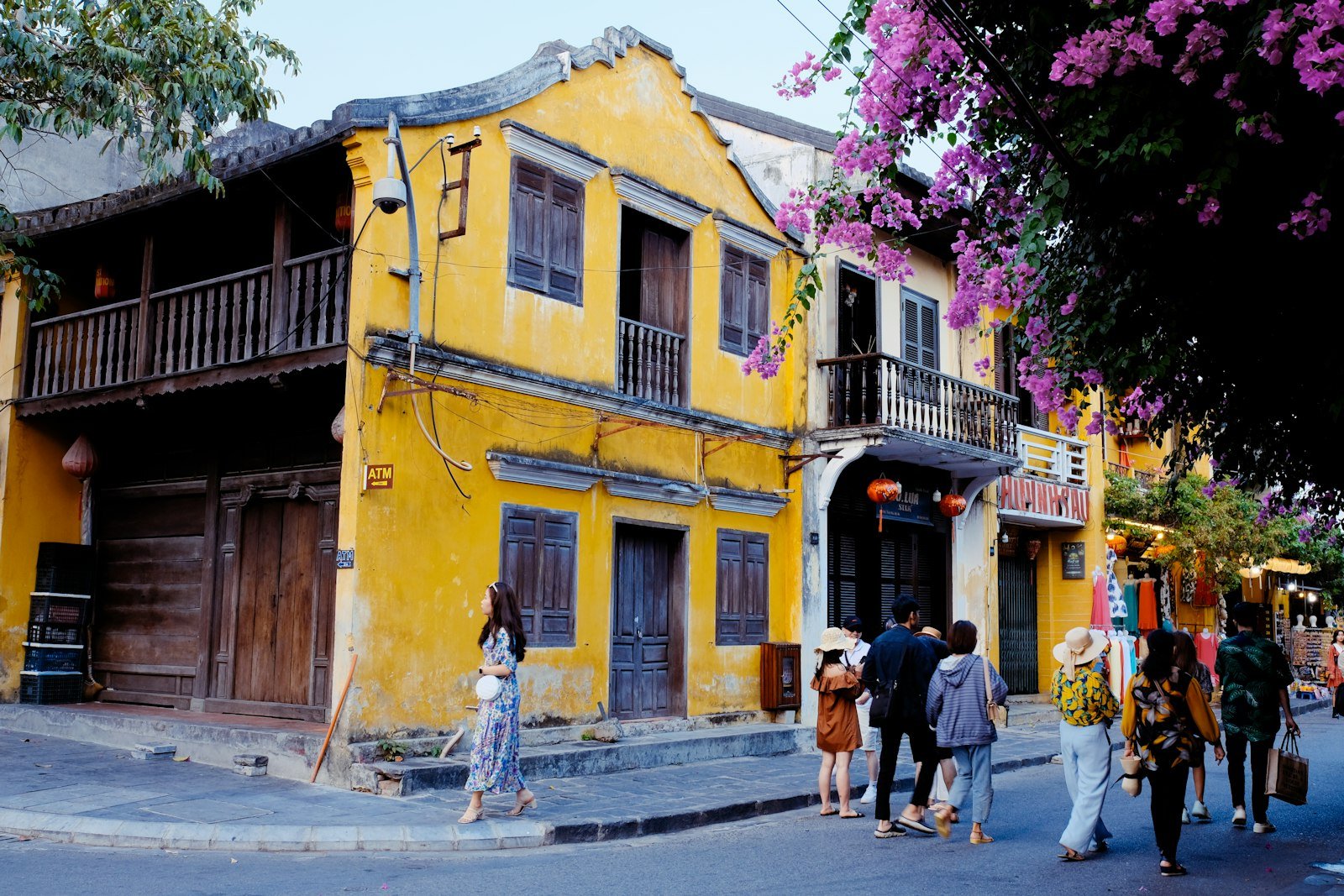 Yellow historic buildings and pedestrians on a street in Hoi An